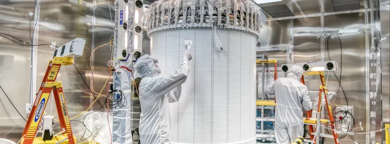 Two researchers in a cleanroom work on a dark matter detector.