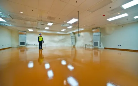 1 person stands in a shiny empty  underground lab space.