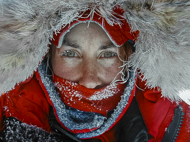 A person's eyes show from beneath a hooded parka.