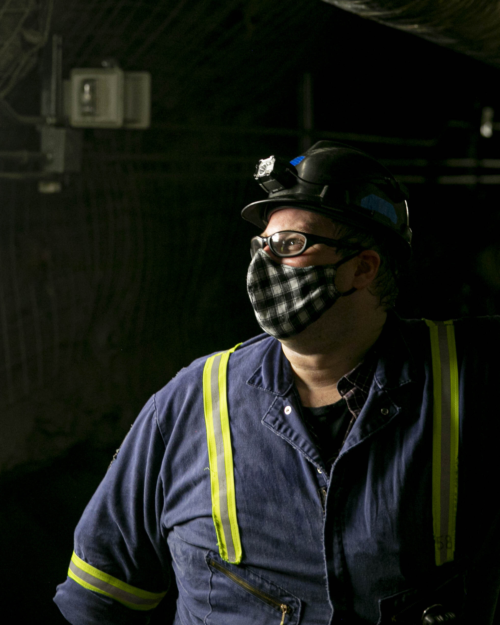 A man wearing a covid-19 mask stands in a dimly lit tunnel