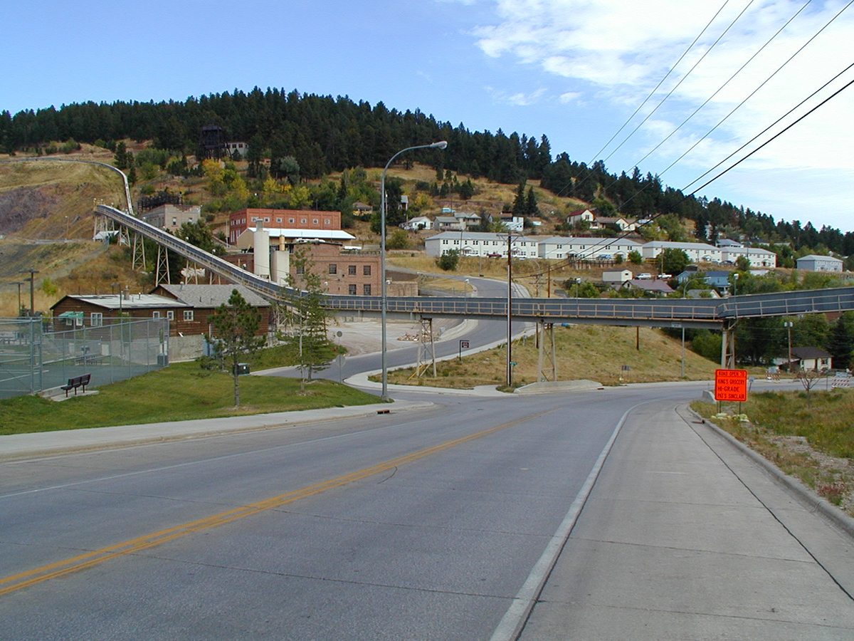 A conveyor system is pictured above a highway running through a small town