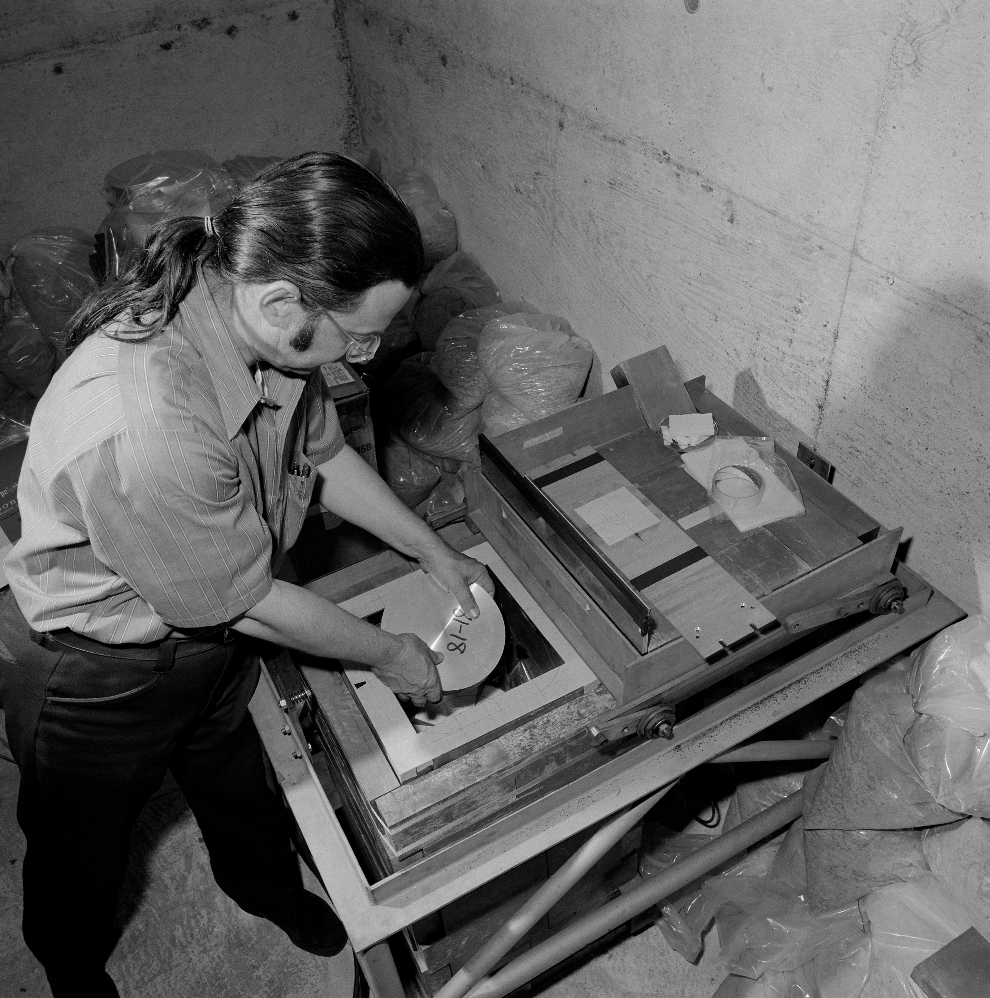 Physicist Al Smith places an aluminum disk sample exposed to radiation a the Bevatron into a lead and concrete box containing a detector at the low-level radiation counting facility.