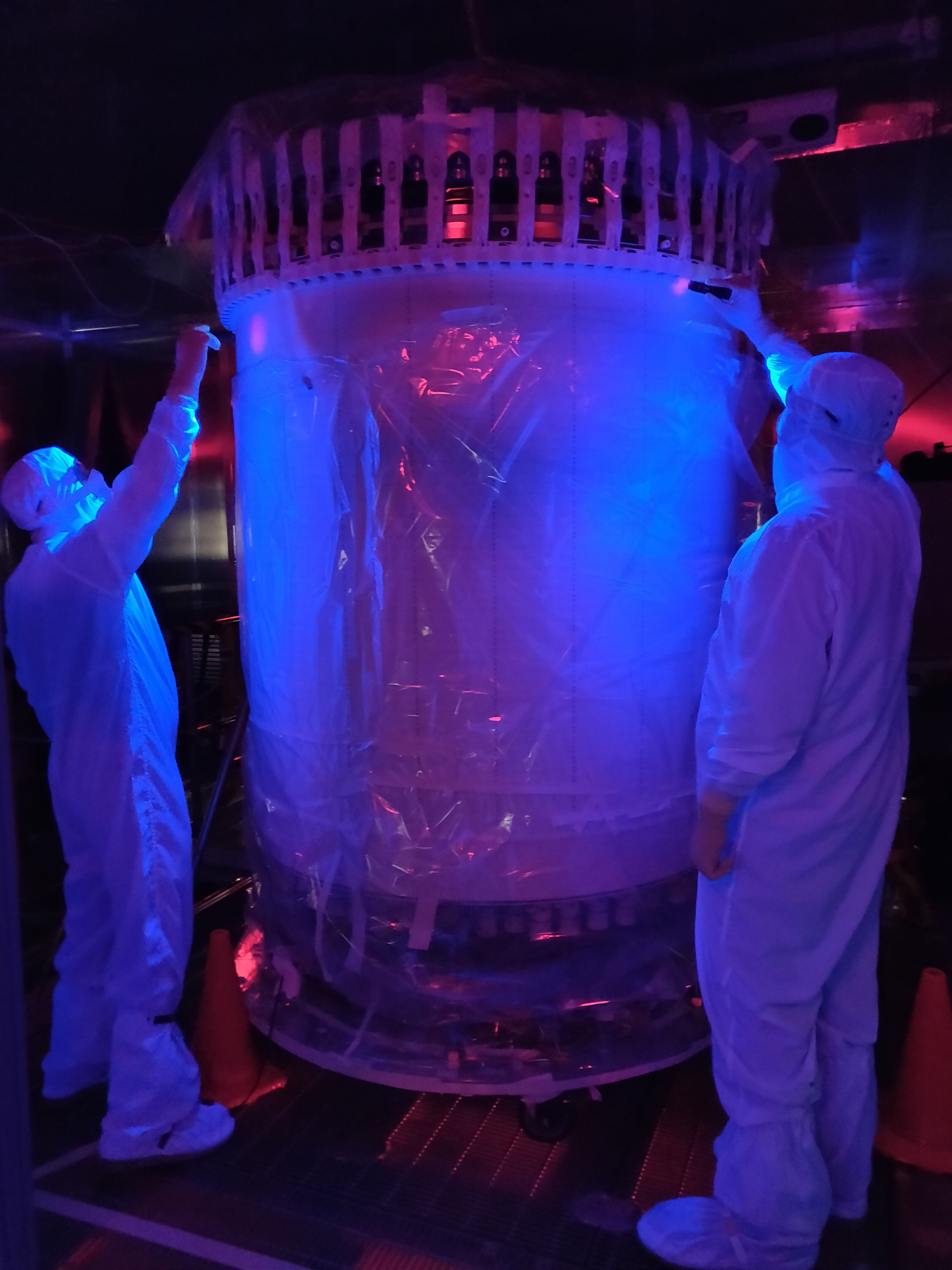 Researchers check for dust on the detector under a black light.
