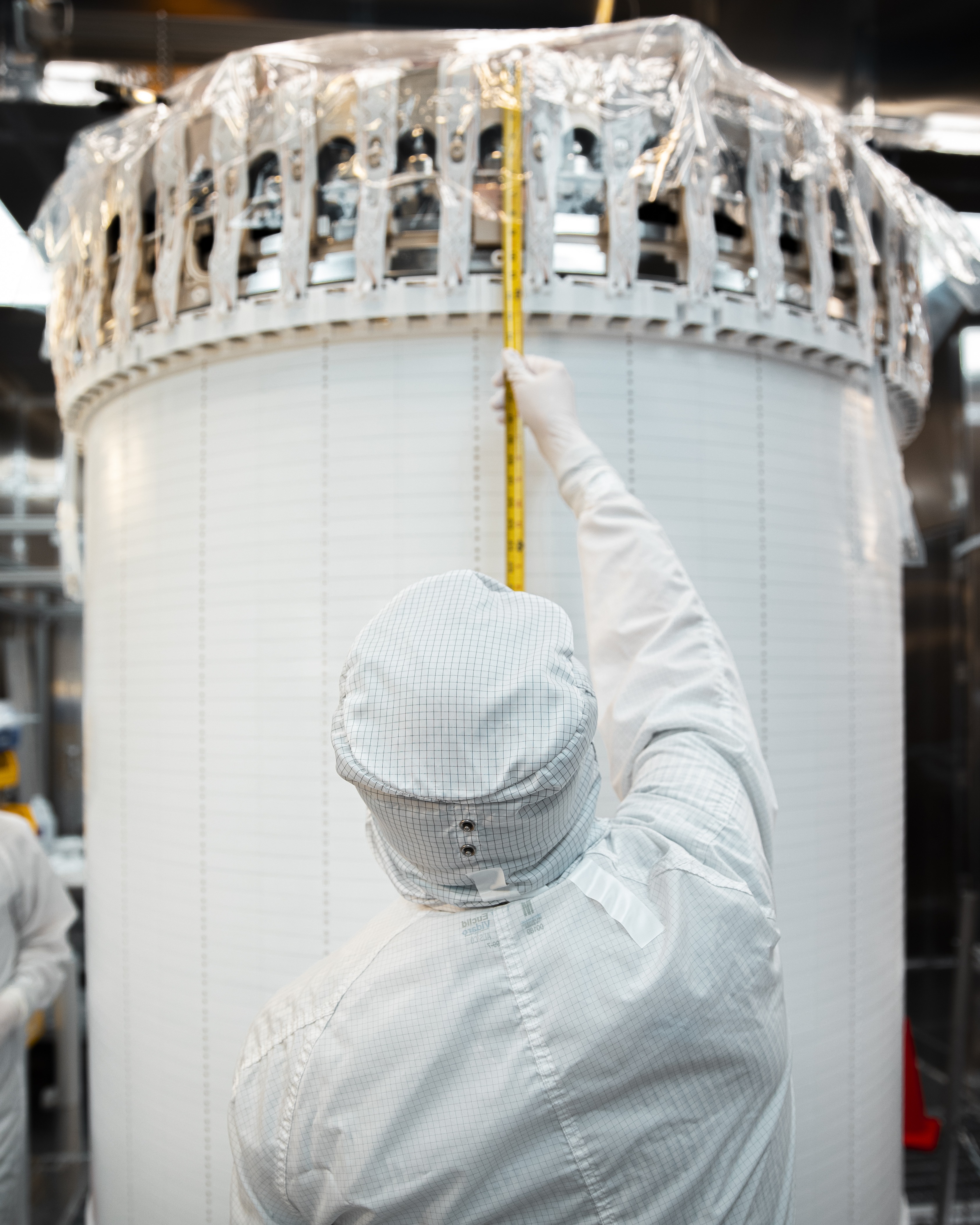 A researcher takes measurements of the recently assembled LUX-ZEPLIN xenon detector in the Surface Assembly Lab cleanroom at Sanford Underground Research Facility on July 26, 2019. Photo by Nick Hubbard, Sanford Underground Research Facility.