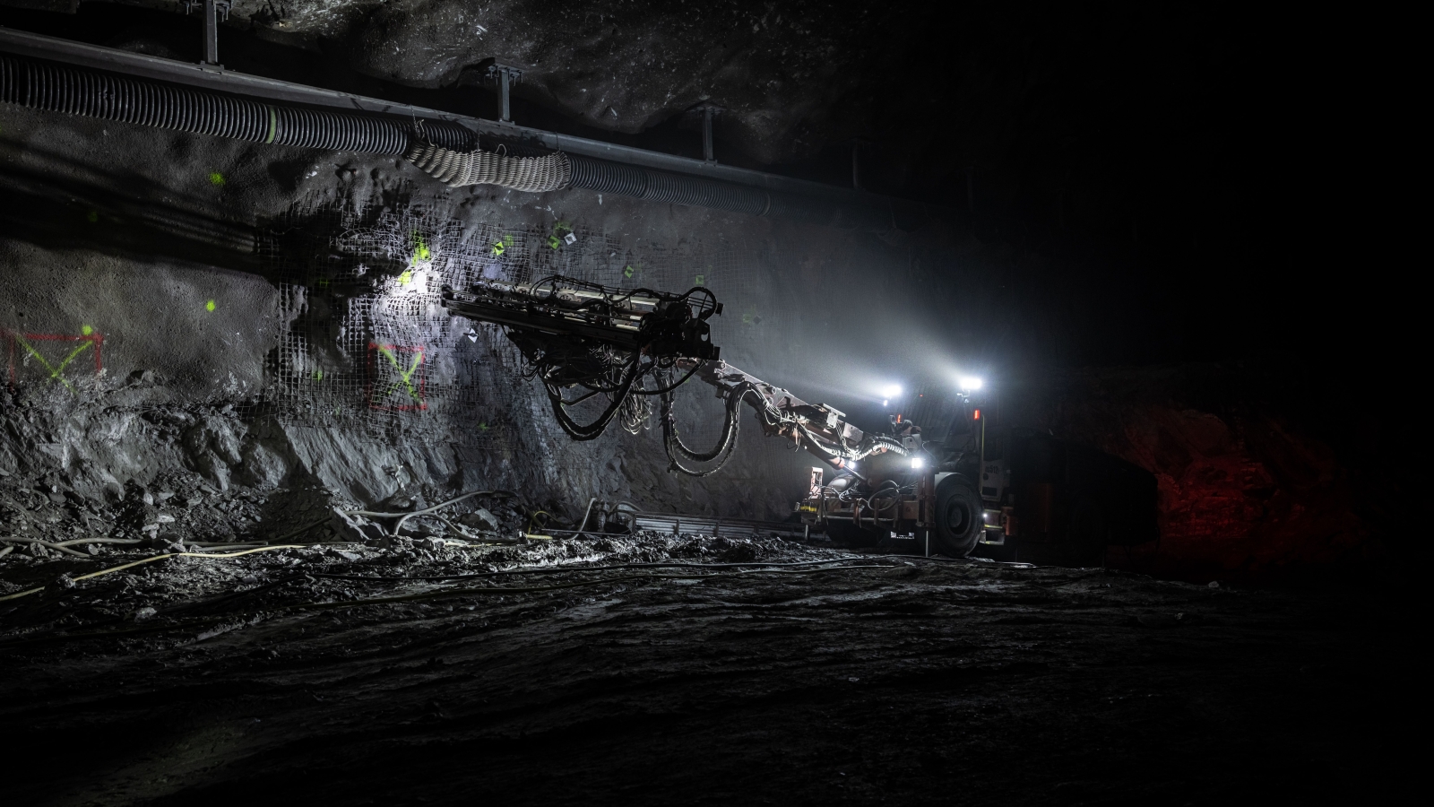 In a large cavern, excavation crew member operates a driller