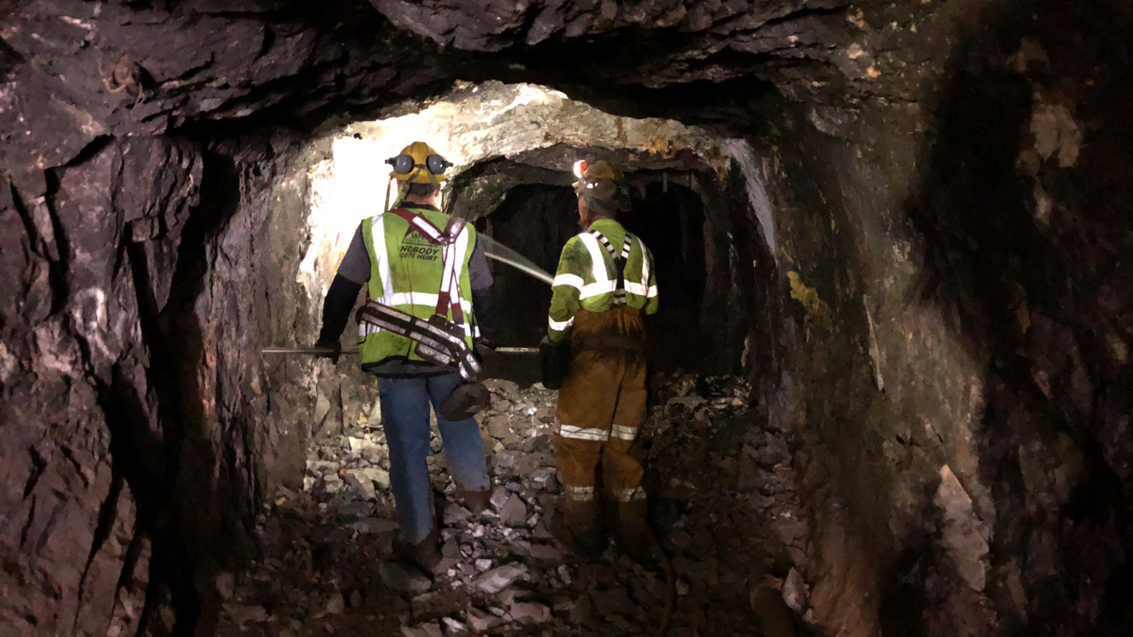 Two workers walk down an illuminated underground tunnel