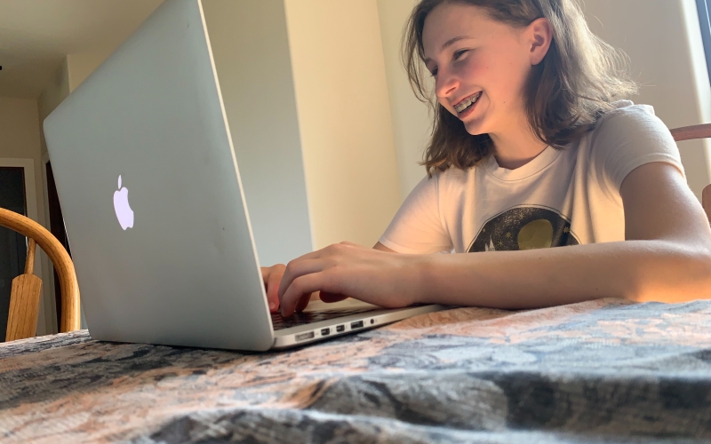 girl smiles while working on computer