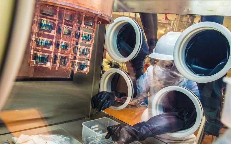 A researcher works on a cryostat inside a glovebox.