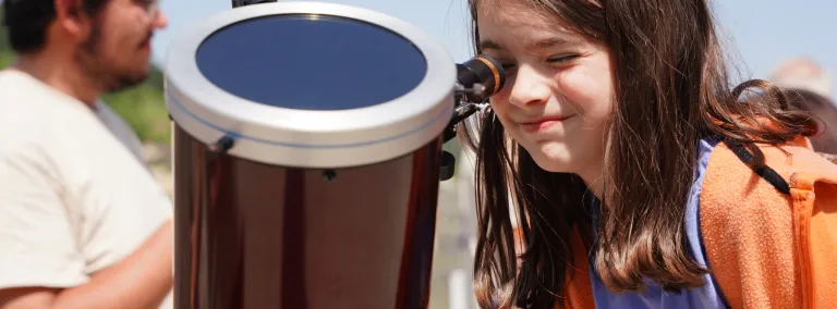 A young persion looks through a telescope 