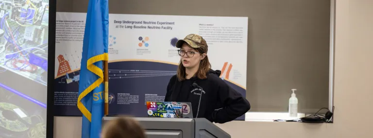 Piper Kinder stands at a podium giving a talk at SURF 