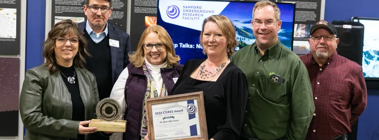A group from the Black Hills Pioneer and SURF gather around the CORE award during the awards presentation
