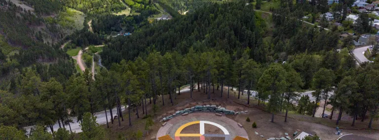 A shot of the Sanford Underground Research Facility (SURF) in the Black Hills showing Čhaŋgléška Wakȟáŋ, the ethnobotanical garden at SURF, and the Ross Headframe.  