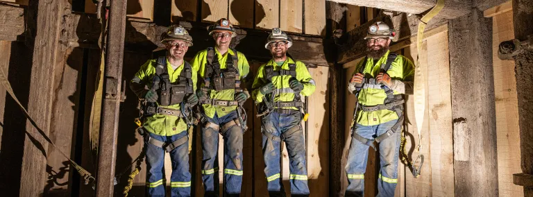 A photo of four members of one of the four crews who completed the Yates TDM.  The crew is wearing PPE, inside the shaft, with large smiles. 