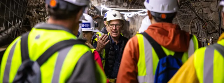 Bill Roggenthen speaks to a group of people in PPE underground. 