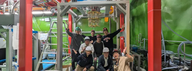 Some members of the TESSERACT collaboration gathered at the Kamioka cryolab in Japan include, (top row): Koji Ishidoshiro (Tohoku U.), Igarashi Satoru (AES/KEK), Burkhant Suerfu (KEK) Middle row: Yuta Imai (Blufors), Maurice Garcia-Sciveres (LBNL) Bottom row: Akira Imai (Blufors), Satoru Miyamoto (Blufors), Khai Bui (KEK).  The group is near a dilution refrigerator and the steel beams supporting the structure.