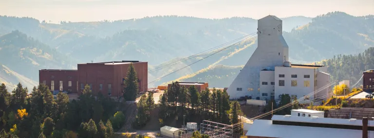 A photo of the the Yates Headframe and Yates Hoistroom at SURF with the Black Hills on a fall day in 2024.     