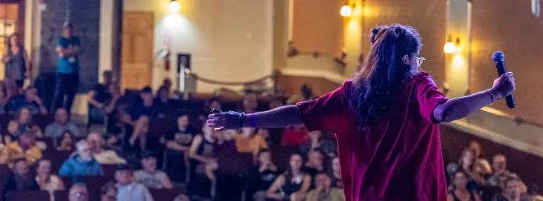 A person in front of a crowd at the 2024 Neutrino Day event inside the Homestake Opera House 