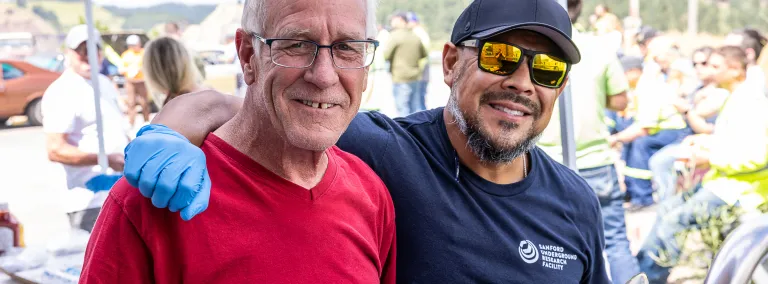 Brett Stenson in a red shirt standing next to Derek Lucero at the Jack Stratton Car/Motorcycle show at SURF in August of 2025. 