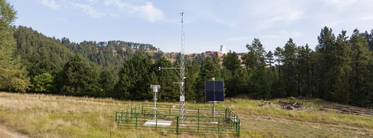TYhe Mesonet weather station in Kirk Canyon with the Yates Headframe in the horison