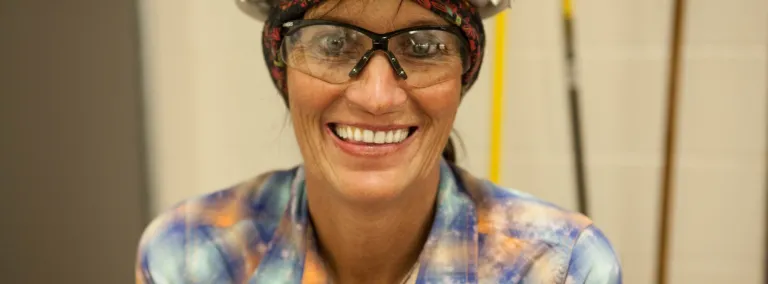 Woman wearing a hardhat smiles at the camera 
