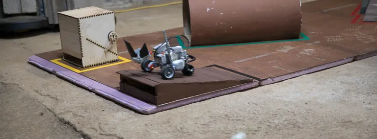 A LEGO robot tosses its payload at the end of the obstacle course