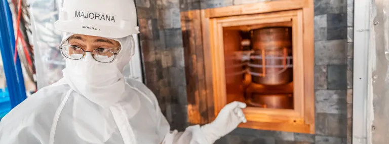 researcher in clean suit point to detector module inside layers of copper and lead shielding