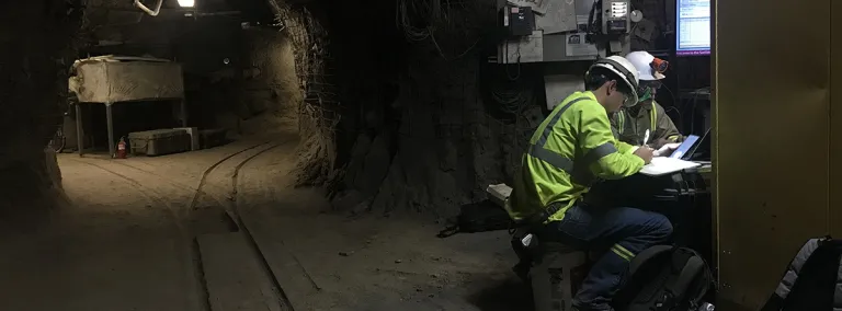 two people in safety gear work in an underground drift 