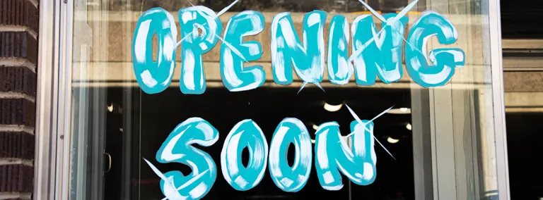 The words "Opening Soon" are written in window pain in a storefront
