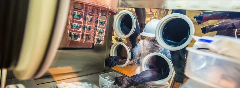 A researcher works on a cryostat inside a glovebox.