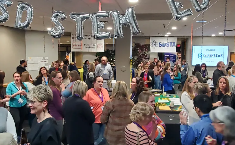  gathering of atendees at the SD STEM ED conference under baloons spelling out SD STEM ED.