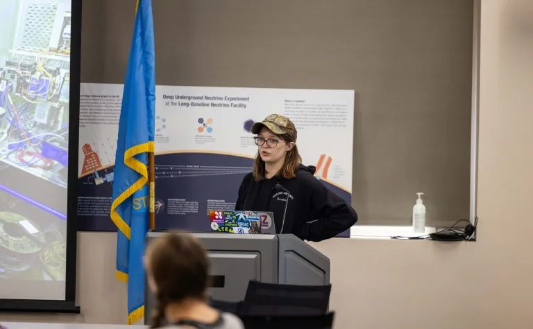 Piper Kinder stands at a podium giving a talk at SURF 