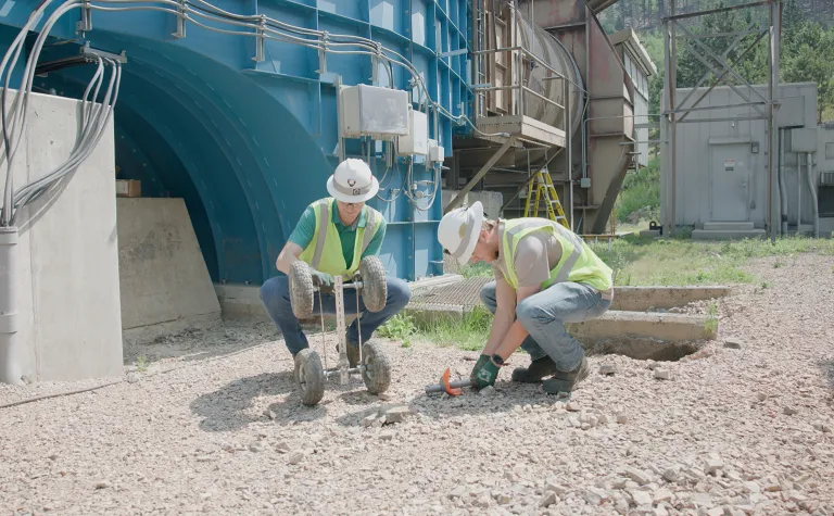 Two 2024 SURF interns work outdoors at the Oro Hondo shaft site in PPE