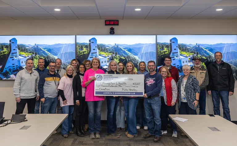 A group photo around a large donation check from SURF to the Foundation for Health