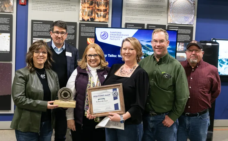 A group from the Black Hills Pioneer and SURF gather around the CORE award during the awards presentation