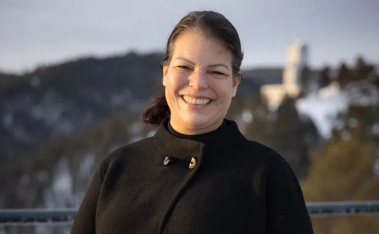 Annie Averitt poses outside at SURF in the winter.  The Ross Headframe is on the hill behind her. 