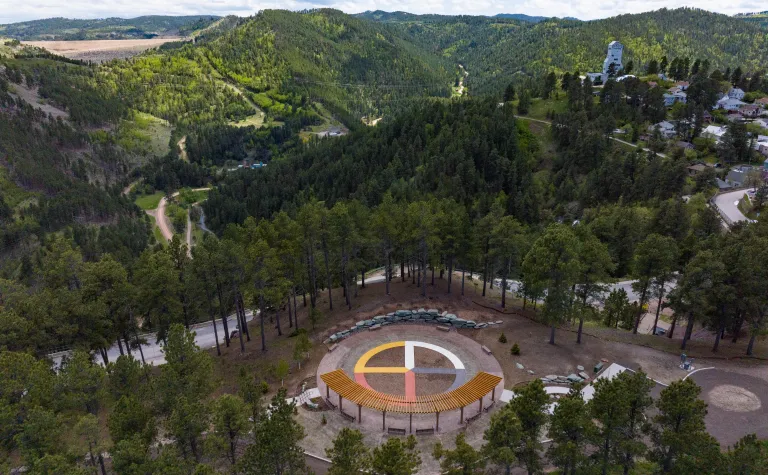 A shot of the Sanford Underground Research Facility (SURF) in the Black Hills showing Čhaŋgléška Wakȟáŋ, the ethnobotanical garden at SURF, and the Ross Headframe.  