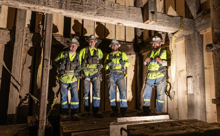 A photo of four members of one of the four crews who completed the Yates TDM.  The crew is wearing PPE, inside the shaft, with large smiles. 