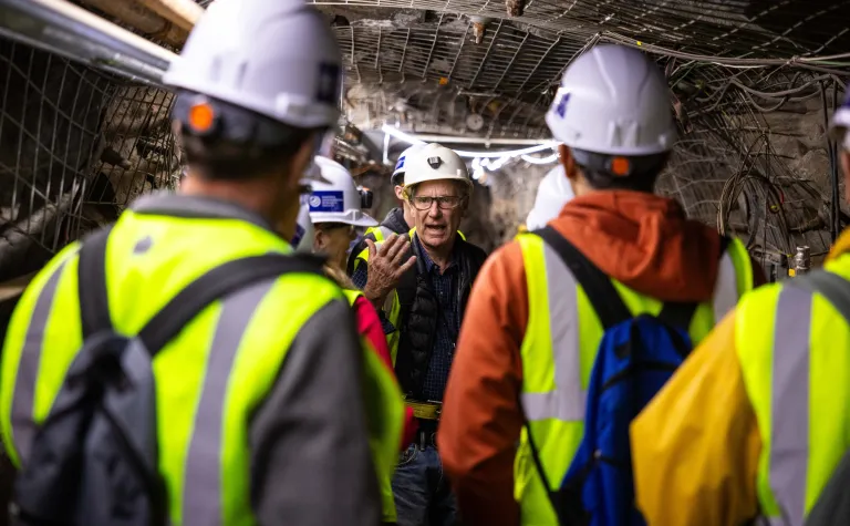 Bill Roggenthen speaks to a group of people in PPE underground. 