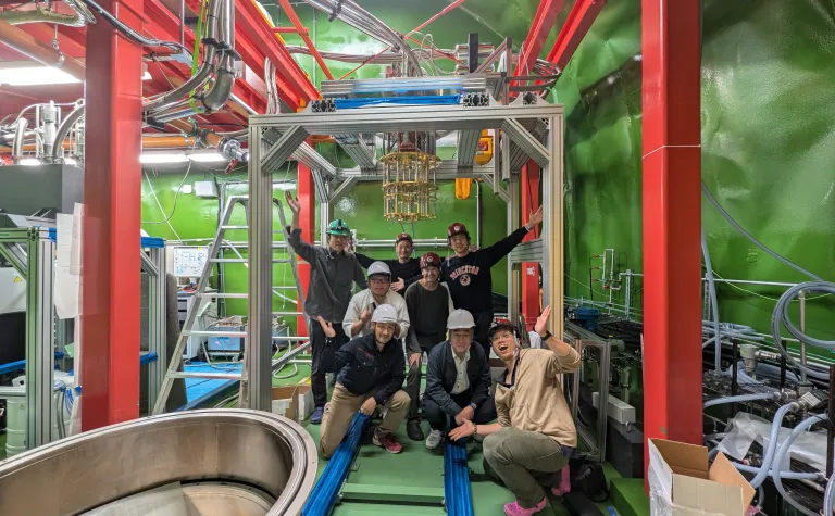 Some members of the TESSERACT collaboration gathered at the Kamioka cryolab in Japan include, (top row): Koji Ishidoshiro (Tohoku U.), Igarashi Satoru (AES/KEK), Burkhant Suerfu (KEK) Middle row: Yuta Imai (Blufors), Maurice Garcia-Sciveres (LBNL) Bottom row: Akira Imai (Blufors), Satoru Miyamoto (Blufors), Khai Bui (KEK).  The group is near a dilution refrigerator and the steel beams supporting the structure.