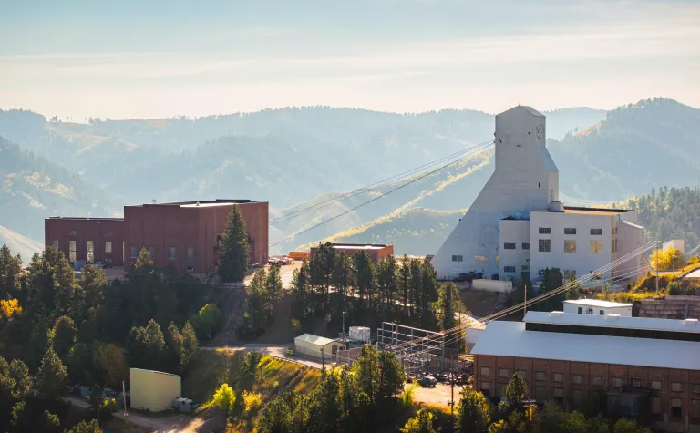 A photo of the the Yates Headframe and Yates Hoistroom at SURF with the Black Hills on a fall day in 2024.     
