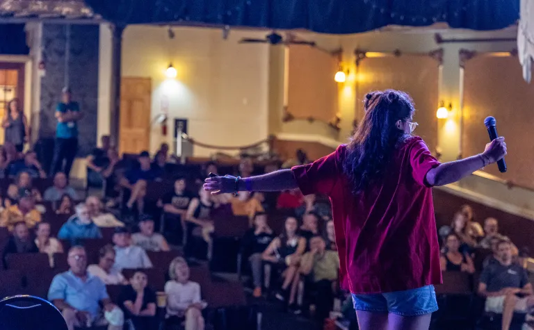 A person in front of a crowd at the 2024 Neutrino Day event inside the Homestake Opera House 