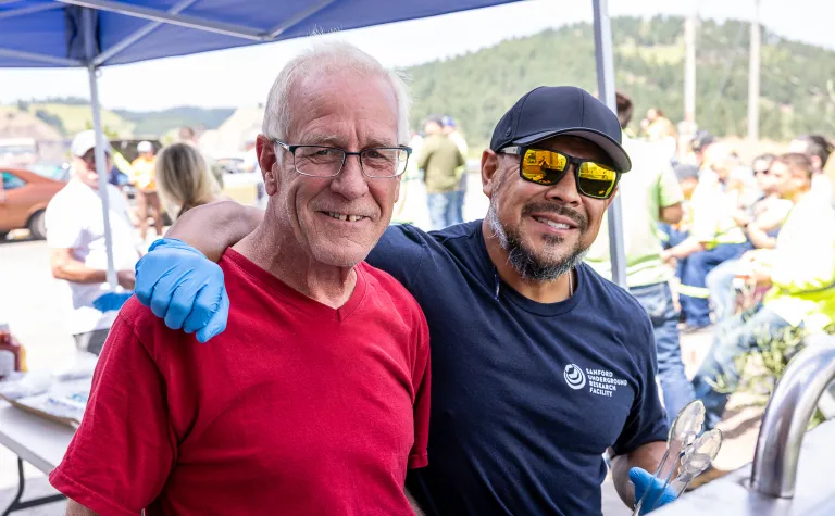 Brett Stenson in a red shirt standing next to Derek Lucero at the Jack Stratton Car/Motorcycle show at SURF in August of 2025. 