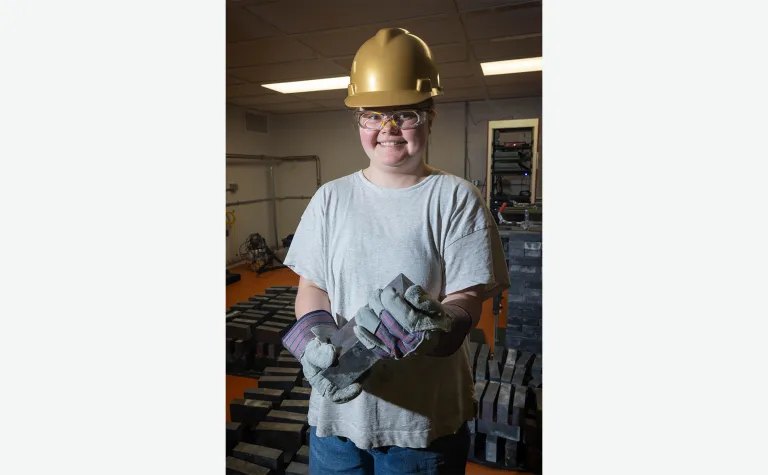 Katie Pedneau poses inside the BHUC holding a brick of led in PPE