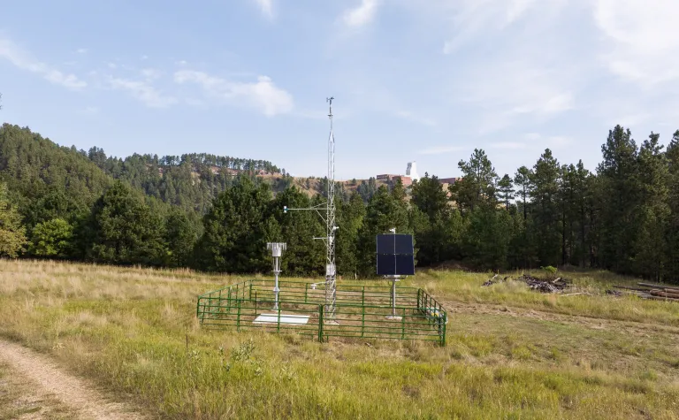 TYhe Mesonet weather station in Kirk Canyon with the Yates Headframe in the horison