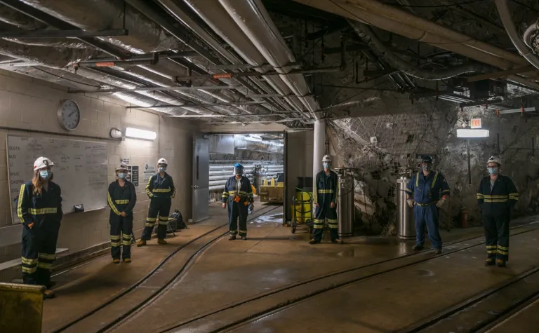 seven people stand 6 feet apart in an underground tunnel