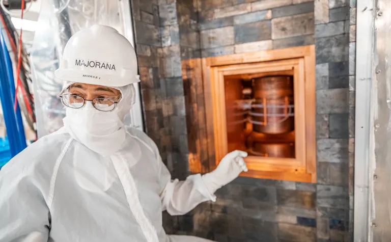 researcher in clean suit point to detector module inside layers of copper and lead shielding
