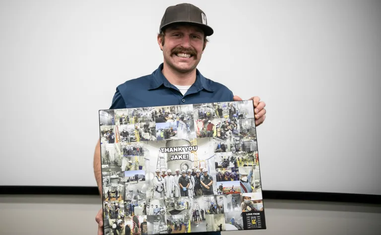 Davis holds a collage of photos with the words "Thank you Jake!" written on it