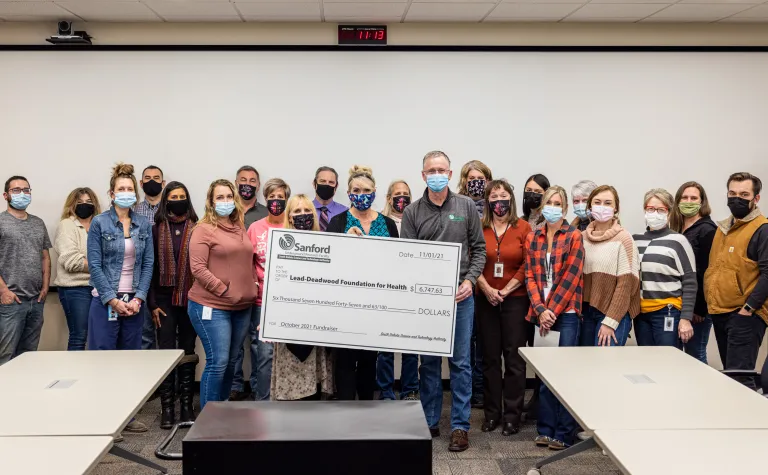 a large group of people hold a giant check