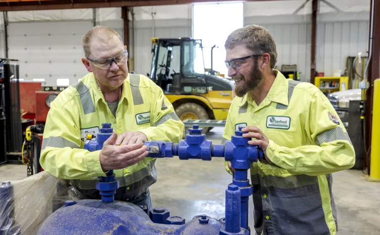 Two workers work on a pump 