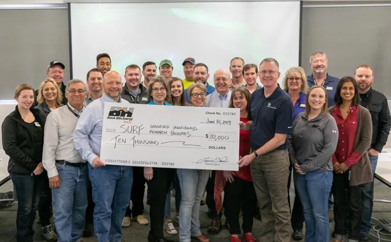 Black Hills Energy presents Sanford Underground Research Facility with a $10,000 check to sponsor Neutrino Day 2019.
